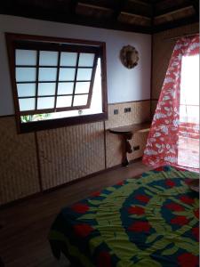 a bedroom with a colorful bed and a window at AU FARE MOENAU in Paea