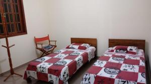 a bedroom with two beds and a chair at Hospedaria Tinoco in Ipiabas +1 photo