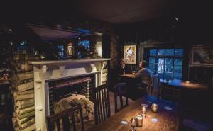a woman sitting at a table in a room with a fireplace at The Marquis of Granby in Alkham