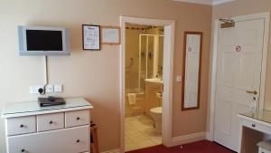 a bathroom with a toilet and a tv on the wall at The Moorings Hotel & Seafood Restaurant in Portmagee