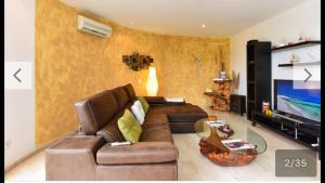 een woonkamer met een bruine bank en een televisie bij Villa Las Terrazas 17•Exclusive Chill Out and Pool. in San Bartolomé