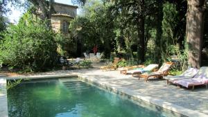 una piscina con sedie a sdraio accanto a una casa di Maison d'Hôtes La Boca a Sommières