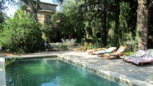 a swimming pool with lounge chairs next to a house at Maison d'Hôtes La Boca in Sommières