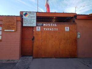 a building with a wooden door with a sign on it at Hostal Tuyasto in San Pedro de Atacama