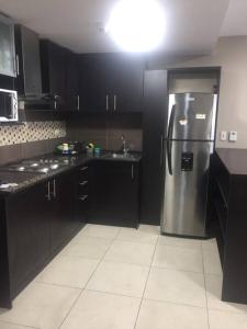 a kitchen with black cabinets and a stainless steel refrigerator at LUXURY APARTMENT PUERTO SANTA ANA GUAYAQUIL in Guayaquil