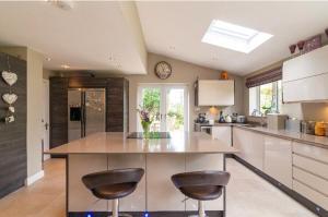 a kitchen with two bar stools and a clock on the wall at Wilmslow Airbnb in Wilmslow