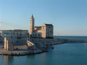 a building with a clock tower next to the water at Travel and Living in Trani