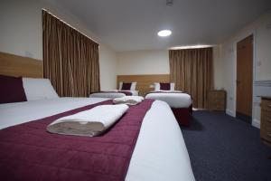 a hotel room with two beds with purple sheets at PremierLux Serviced Apartments in Ilford