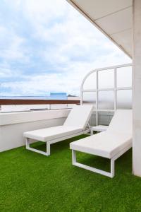 
a row of white chairs sitting on top of a grass covered field at Hotel Inglaterra in Seville
