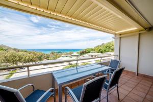 a balcony with a table and chairs and the ocean at Samarinda Jewel by the Sea in Point Lookout