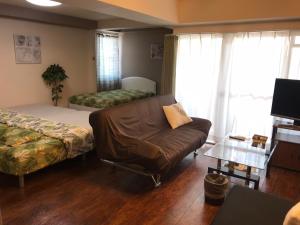 een woonkamer met een bank, een bed en een tafel bij Lipelala Stay 505 in Osaka
