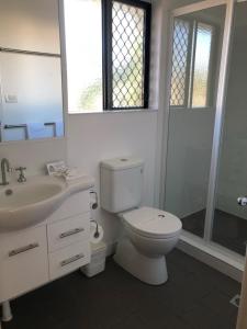 a white toilet sitting next to a sink in a bathroom at Biloela Palms Motor Inn in Biloela