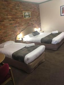 a hotel room with two beds and a brick wall at Pines Country Club Motor Inn in Shepparton