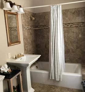 a bathroom with a sink and a tub and a shower curtain at Riverside Hot Springs Inn & Spa - Adults Only in Lava Hot Springs