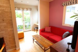 a living room with a red couch and a table at Tabinoteitaku Kamakura Yuigahama -Homann Concept- in Kamakura