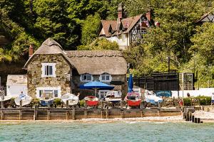 a house with boats parked outside of it next to the water at Cliff Top Apartment 3 Bedroom in Shanklin