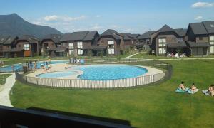 un grupo de personas sentadas en el césped alrededor de una piscina en Departamento en Pucon, en Pucón