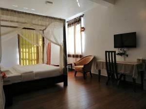 a bedroom with a bed and a table and a television at Melford Nuwaraeliya in Nuwara Eliya