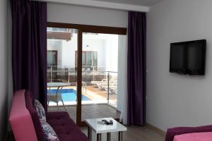 ein Wohnzimmer mit einem lila Sofa und einem TV in der Unterkunft Siesta Garden Apart Hotel in Turgutreis