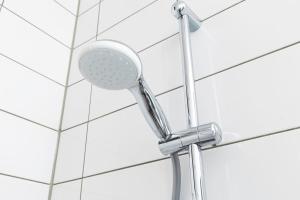 a shower with a shower head on a white tile wall at New Loft Apt View Delft city center balcony Utopia2c in Delft