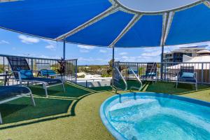 a swimming pool with a patio area with chairs and umbrellas at Beach Club Resort Mooloolaba in Mooloolaba