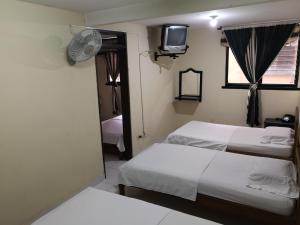 a bedroom with two beds and a tv on the wall at Hotel Alferes Ibagué in Ibagué