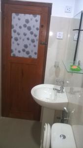 a bathroom with a sink and a toilet and a door at Ella Breeze Homestay in Ella