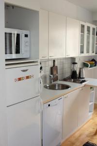 a white kitchen with a sink and a refrigerator at Cozy studio at the center of Lahti in Lahti