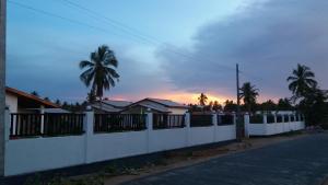 une clôture blanche devant une maison plantée de palmiers dans l'établissement JEYs Place, à Nilaveli