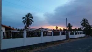 a white fence in front of a house with palm trees at JEYs Place in Nilaveli