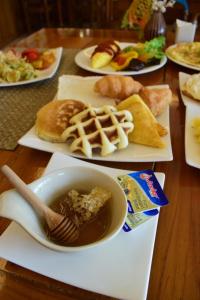 a table topped with plates of food with a bowl of syrup at Villa Sirilanna Hotel in Chiang Mai