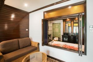 a bathroom with a tub and a chair and a mirror at Villa Sirilanna Hotel in Chiang Mai