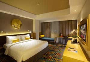 CibuburHotel Ciputra Cibubur managed by Swiss-Belhotel International的配有一张大床和一张书桌的酒店房间