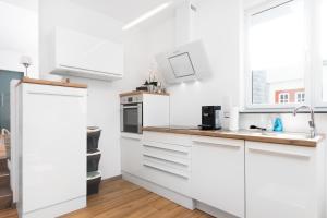 a white kitchen with white cabinets and a wooden floor at eifel5starIII- Burgfriedstraße in Daun