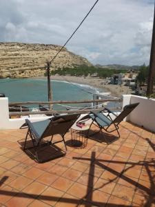 a group of chairs sitting on a patio next to a beach at Absolute Matala in Matala
