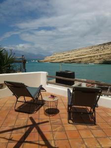 two chairs and a table on a patio near the water at Absolute Matala in Matala