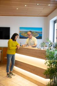 a man and a woman standing behind a reception desk at Mittelrhein Pension in Boppard