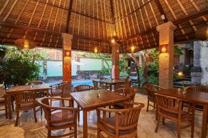 un restaurante al aire libre con mesas y sillas de madera en Ellies Hotel, en Nusa Dua