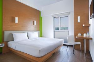 a bedroom with a white bed and a desk and a window at Amaris Hotel Embong Malang - Surabaya in Surabaya