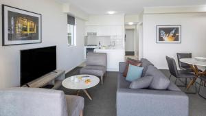 ein Wohnzimmer mit einem Sofa, einem TV und einem Tisch in der Unterkunft Oaks Brisbane on Margaret Suites in Brisbane