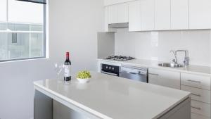eine weiße Küche mit einer Flasche Wein auf der Theke in der Unterkunft Oaks Brisbane on Margaret Suites in Brisbane