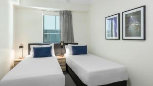 two beds in a room with a window at Oaks Brisbane on Margaret Suites in Brisbane