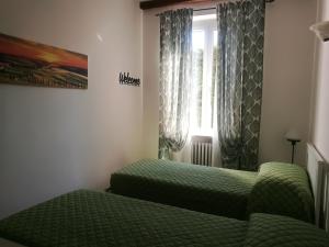 a bedroom with two green beds and a window at Il Melograno in Torrita di Siena