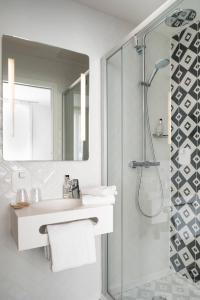a white bathroom with a sink and a shower at Hotel des Lys in Versailles +20 photos