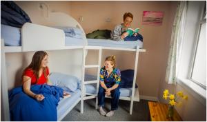 two children are sitting on a bunk bed at Loch Ness Lochside Hostel in Invermoriston