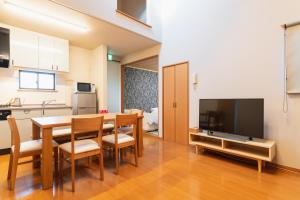 a kitchen and dining room with a table and a television at Ecol Beppu in Beppu