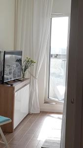 een woonkamer met een raam en een televisie op een dressoir bij Aquamarina Onyx 109 in Międzyzdroje