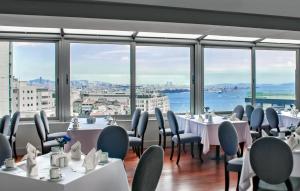 een restaurant met tafels en stoelen en grote ramen bij Taksim Square Hotel in Istanbul