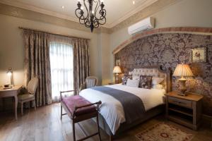 a bedroom with a large bed and a chandelier at Three Rivers Lodge and Villas in Vereeniging