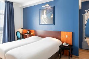 une chambre d'hôtel avec un lit et un mur bleu dans l'établissement Hotel des Lys, à Versailles